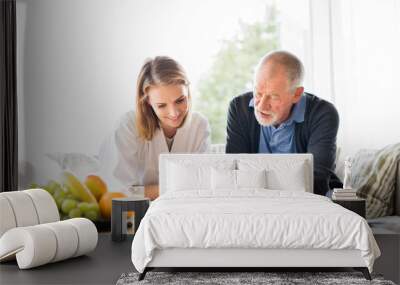 Health visitor and a senior man with tablet during home visit. Wall mural