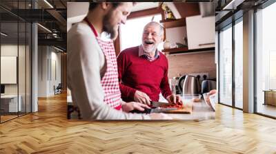 Hipster son with his senior father cooking in the kitchen. Wall mural