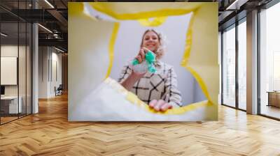 Image from inside yellow recycling bag of woman throwing a plastics to recycle. Wall mural