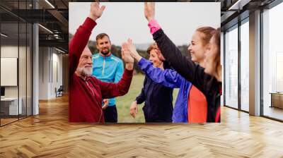 Large group of fit and active people resting after doing exercise in nature. Wall mural