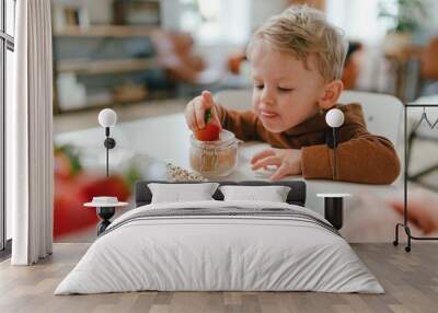 Little boy eating homegrown strawberries with brown sugar. Wall mural