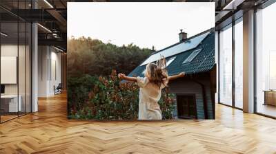 Little girl in front of house with solar panels on roof, jumping, dancing and having fun. Concept of renewable resources. Wall mural