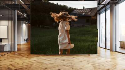 Little girl in front of house with solar panels on roof, jumping, dancing and having fun. Concept of renewable resources. Wall mural