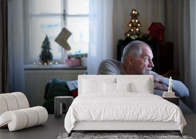 Lonely senior man sitting on sofa indoors at Christmas, solitude concept. Wall mural