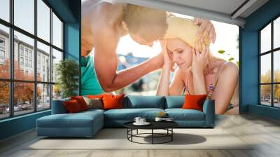 man helping woman in bikini with heatstroke, summer heat Wall mural