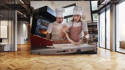 Man with down syndrom helping prepair bread in bakery with his colleague. Concept of integration people with disability into society. Wall mural