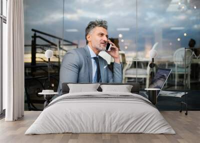 Mature businessman with smartphone in an outdoor hotel cafe. Wall mural