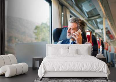 Mature businessman with smartphone travelling by train. Wall mural