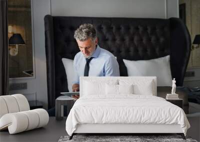 Mature businessman with tablet in a hotel room. Wall mural