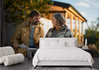 Mature couple having coffee break when working together on construction site of their new house. Wall mural