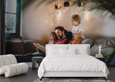 Mature father with two small children resting indoors at home, looking at photo album. Wall mural