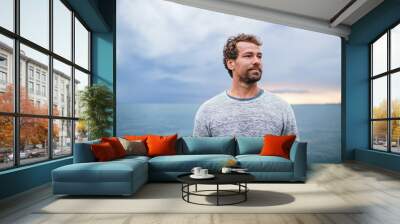 Mature man standing outdoors on beach at dusk. Wall mural