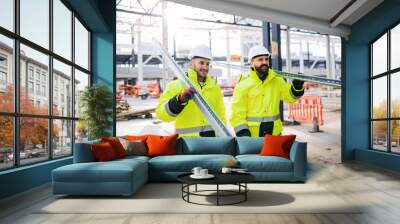 Men workers walking outdoors on construction site, working. Wall mural