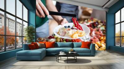 Midsection of a woman putting food on plate on a indoor family birthday party. Wall mural