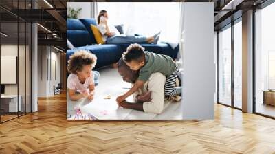 Multi ethnic family with two small children drawing pictures, home office. Wall mural