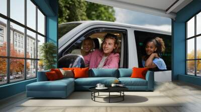 Multiracial young friends travelling together by car, looking through window and smiling - summer vacation, holidays, travel, road trip and people concept. Wall mural