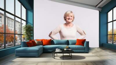 Portrait of a happy senior woman in studio. Wall mural