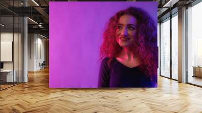 Portrait of a happy young woman dancing over neon light background at disco party Wall mural