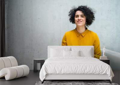 Portrait of a young student or businesswoman sitting on desk in room in a library or office. Wall mural