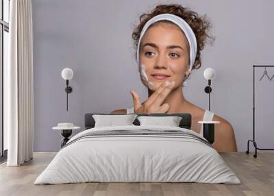 Portrait of a young woman cleaning face in a studio, beauty and skin care. Wall mural