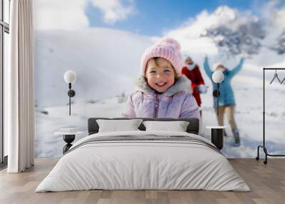 Portrait of cheerful small girl playing in snow in winter nature, playing. Wall mural