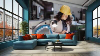 Portrait of female chief engineer in modern industrial factory using tablet and machine. Wall mural