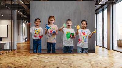 Portrait of happy kids with finger colours and painted t-shirts, studio shoot. Wall mural