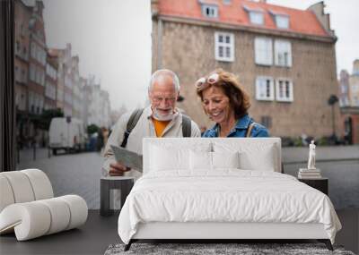 Portrait of happy senior couple tourists using map outdoors in town street Wall mural