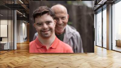 Portrait of happy senior father with his young son with Down syndrome outdoors. Wall mural