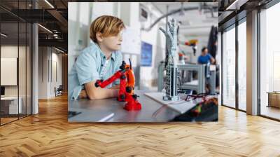 Portrait of schoolboy looking robotic arm and hand, after-school robotics club. Children learning robotics in Elementary school. Science for kids. Wall mural