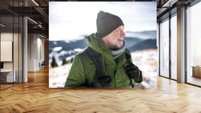 Portrait of senior man standing in snow-covered winter nature. Wall mural