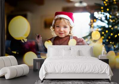 Portrait of small girl indoors at home at Christmas, painting pictures. Wall mural