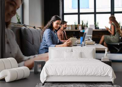 Portrait of young businesspeople with laptop working indoors in office. Wall mural