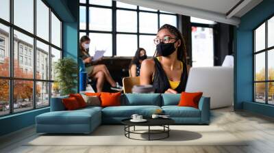 Portrait of young businesswoman with face mask working indoors in office. Wall mural