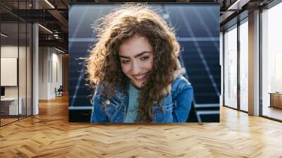 Portrait of young woman on roof with solar panels. Wall mural