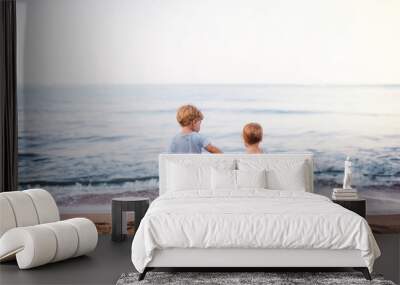 Rear view of two toddler children playing on sand beach on summer holiday. Wall mural