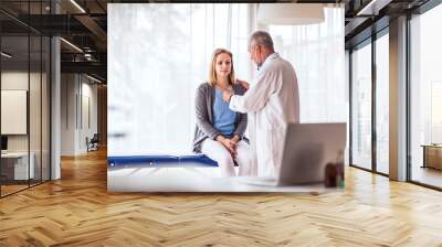 Senior doctor examining a young woman in office. Wall mural