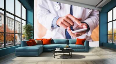 Senior doctor with smartphone working at the office. Wall mural