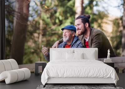 Senior father and his son on walk in nature, standing and talking. Wall mural