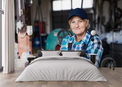 senior female mechanic repairing a car in a garage. Wall mural