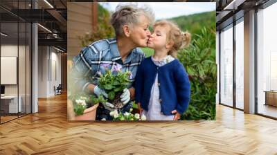 Senior grandmother with small granddaughter gardening on balcony in summer. Wall mural