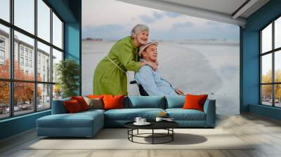 Senior man on wheelchair enjoying together time with his wife at sea. Wall mural