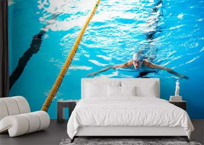 Senior man swimming in an indoor swimming pool. Wall mural