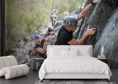 Senior man with instructor climbing rocks outdoors in nature, active lifestyle. Wall mural