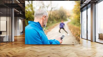 senior runners in nature, stretching. man with smartphone with e Wall mural