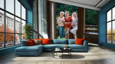 Senior women friends standing outdoors on terrace, resting. Wall mural