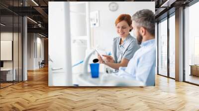 Side view of dentist talking to man in dentist surgery, a dental check-up. Wall mural