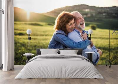 Side view of senior couple hugging outside in spring nature at sunset. Wall mural