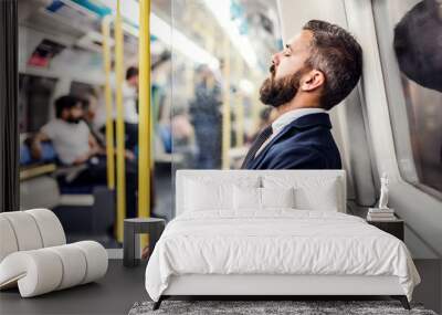 Sleeping hipster businessman inside the subway in the city, travelling to work. Wall mural