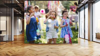 Small children outdoors in garden in summer, playing with bubbles. Wall mural